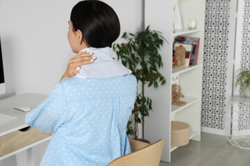 Wall Mural - Woman using heating pad on neck at home