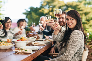 Wall Mural - Toast, dinner and family with a group of people enjoying a meal together while drinking alcohol outdoor. Portrait, party and cheers with a female and relatives bonding in festive celebration