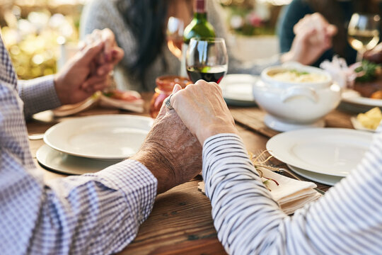 Dinner, holding hands and family prayer at table for thanksgiving celebration with faith, religion and holiday gratitude. Love, social and hand holding of people praying for party, food and wine