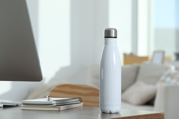 Poster - Stylish thermo bottle on wooden table at workplace in office