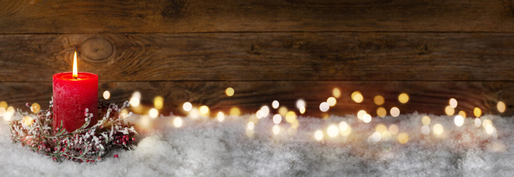 Fototapete - Christmas candle in winter snow landscape with magic lights. Xmas Panorama, Banner. First Advent Sunday. Wood background with copy space.