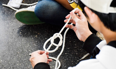 A boy trying to untie a knot or maybe creating it