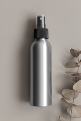 Wall Mural - Aluminium cosmetic spray bottle mockup with an eucalyptus on the beige background.