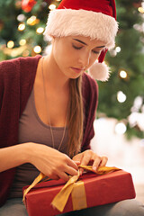 Canvas Print - Christmas, gift and woman on floor in living room on xmas eve, content and calm while wrapping ribbon. Festive, holiday and girl open present box in celebration of traditional holiday in her home