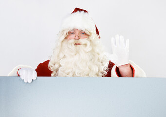 Canvas Print - Christmas, santa and portrait with hand wave for friendly festive holiday greeting advertising. Celebration, vacation and santa claus man waving hello with white studio marketing mockup background.