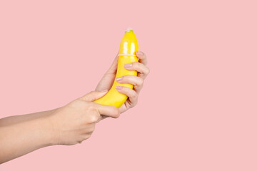 Woman's hand shows how to put a condom on the penis using a banana as a demonstration.