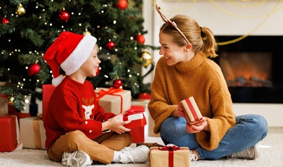 Poster - Cute child and smiling mother opening christmas presents together