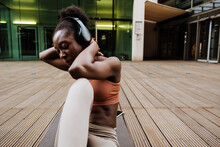 Young Beautiful African Woman In Headphones Exercising On Yoga Mat