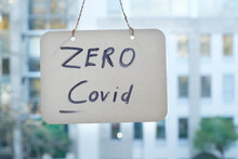 Zero Covid Sign On Window, Office Buildings In The Back
