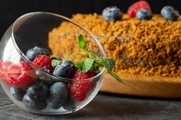 carrot cake decorated with blueberries and raspberries on a dark background