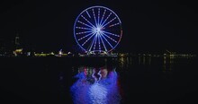Ferris Wheel Flashing Red White And Blue Reflecting In Water