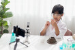 © FAMILY STOCK - Asian school girl making easy chemistry experiments and recording a video for his followers, Young blogger kid posing in front of camera for vlog, Children make vlog for social media channel concept.