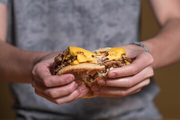 Sticker - Closeup of a man cutting a cheeseburger by hand