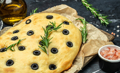 Wall Mural - Close up Italian Focaccia with black olives and rosemary. Food recipe background