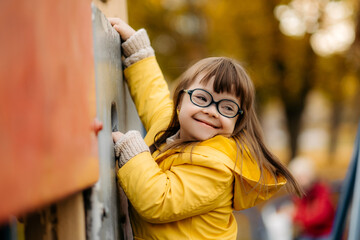 happy child with down syndrome enjoying swing on playground