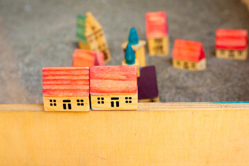 Two small wooden toy houses on border. Children game. Cottages with red roof on grey soil. Modelling village. Construction and architectural concept. City in miniature. Creativity