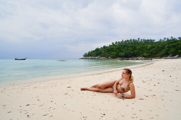 Wall Mural - Vacation on the seashore. Young woman lying on the beautiful tropical beach.