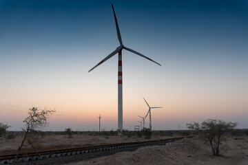 Wall Mural - Pre dawn light in desert sky with Electrical power generating wind mills producing alterative eco friendly green energy for consumption by local people. Thar desert, Rajasthan, India.