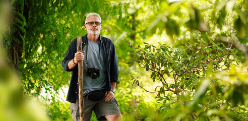 Mature male traveler in green forest. Walk along the green route. Adventure is ageless.