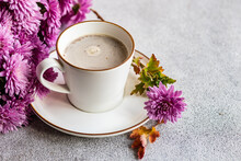 Close-up Of A Cup With Coffee With Milk And Purple Chrysanthemum Flowers On A Table