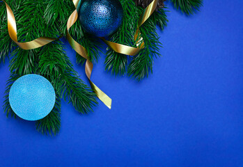 Wall Mural - christmas tree branch with blue balls on an empty blue background