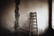 Rusty Metal Step Ladder Against Wall In Empty Room Of Old House