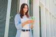 © Jose Calsina - Smiling young woman using mobile phone app , texting, playing game, shopping online, ordering delivery. Happy millennial teen girl sharing social media holding smartphone outdoors. High quality photo