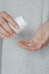 Close up of female hands pouring medicine tablets from bottle into her hand