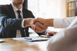 © Pormezz - hand of client and banker shaking hands  on the meeting table after business investment budget done