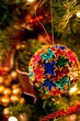 Vertical closeup of a colorful origami ornament on a Christmas tree