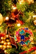 Vertical closeup of a colorful origami ornament on a Christmas tree