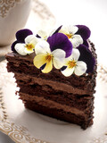 Fototapeta Desenie - Portion of chocolate cake decorated with spring flowers - rustic style