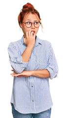 Wall Mural - Young redhead woman wearing casual clothes and glasses looking stressed and nervous with hands on mouth biting nails. anxiety problem.