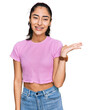 © Krakenimages.com - Hispanic teenager girl with dental braces wearing casual clothes smiling cheerful presenting and pointing with palm of hand looking at the camera.