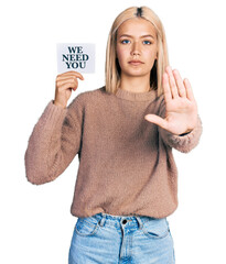 Sticker - Beautiful young blonde woman holding we need a change banner with open hand doing stop sign with serious and confident expression, defense gesture