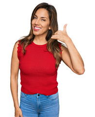 Sticker - Young hispanic woman wearing casual clothes smiling doing phone gesture with hand and fingers like talking on the telephone. communicating concepts.