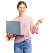© Krakenimages.com - Beautiful caucasian woman with blonde hair working using computer laptop smiling happy pointing with hand and finger to the side