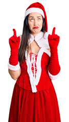 Sticker - Young beautiful caucasian woman wearing santa claus costume pointing up looking sad and upset, indicating direction with fingers, unhappy and depressed.