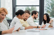 © LIGHTFIELD STUDIOS - asian woman pointing at digital tablet near multicultural business team working on blurred foreground