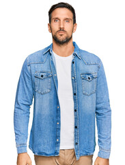 Wall Mural - Young handsome man wearing casual denim jacket relaxed with serious expression on face. simple and natural looking at the camera.