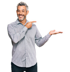 Canvas Print - Middle age grey-haired man wearing casual clothes amazed and smiling to the camera while presenting with hand and pointing with finger.