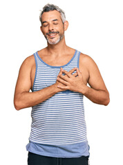 Canvas Print - Middle age grey-haired man wearing casual style with sleeveless shirt smiling with hands on chest with closed eyes and grateful gesture on face. health concept.