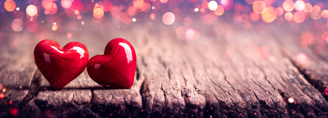 Wall Mural - two red marbled glass hearts on rustic wooden table with soft pink bokeh - valentine's day