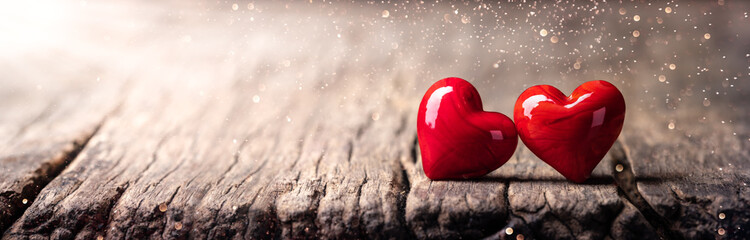 Wall Mural - two red marbled glass hearts on rustic wooden table with sunlight and bokeh - valentine's day
