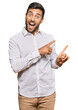 © Krakenimages.com - Handsome hispanic man wearing business clothes smiling and looking at the camera pointing with two hands and fingers to the side.