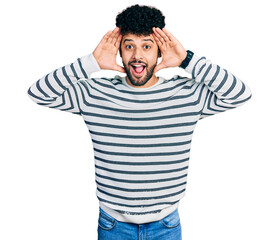 Canvas Print - Young arab man with beard wearing casual striped sweater smiling cheerful playing peek a boo with hands showing face. surprised and exited