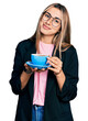 © Krakenimages.com - Hispanic young woman drinking a cup of coffee relaxed with serious expression on face. simple and natural looking at the camera.