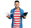 © Krakenimages.com - Young hispanic man with beard using drone with remote control smiling and laughing hard out loud because funny crazy joke.