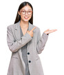 © Krakenimages.com - Young chinese woman wearing business clothes amazed and smiling to the camera while presenting with hand and pointing with finger.