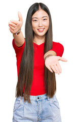 Wall Mural - Young chinese woman wearing casual clothes looking at the camera smiling with open arms for hug. cheerful expression embracing happiness.